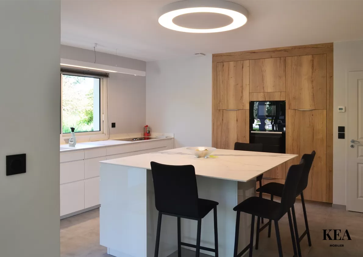 Cuisine sur mesure dans une maison à Charly. Ilot central, cuisine blanche et bois. Plan de travail en Dekton. Cuisine toute équipée à Lyon